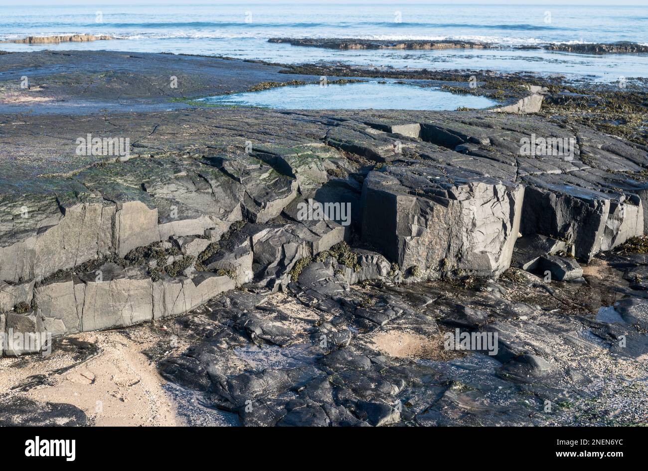 Geologische Ausgrabung schwarzer igneöser Felsen nördlich von Bamburgh, Northumberland, England, Vereinigtes Königreich Stockfoto