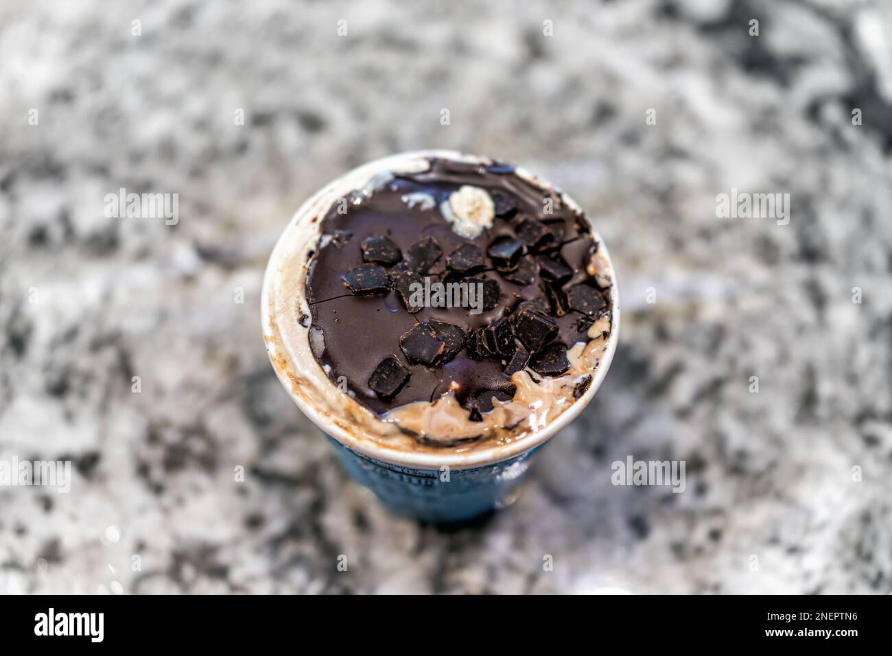 Gefrorenes Eis mit Schokoladen-Ganache auf einem gewöhnlichen Pint-Tubenbehälter auf dem Küchentisch Bokeh-Hintergrund mit Konsistenz von Keksbrownie p Stockfoto