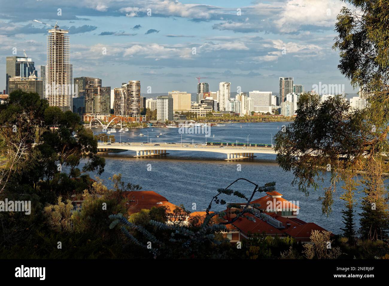 Blick auf das Zentrum von Perth in Westaustralien, Landschaft mit Wolkenkratzern, Parks und Bucht mit Brücke bei Sonnenuntergang oder Sonnenaufgang. Wolken auf der Straße Stockfoto
