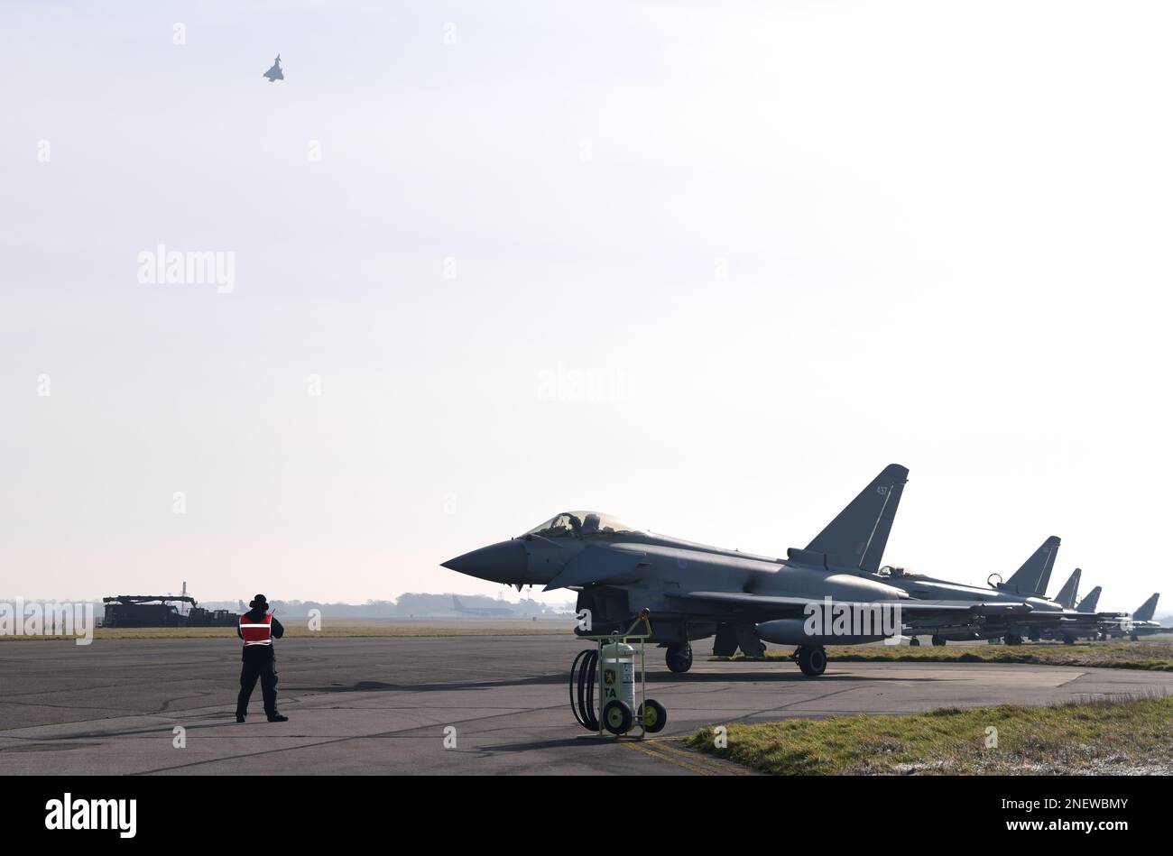 Ein Mitglied des Team Mildenhall aus dem Transitalarm bereitet sich darauf vor, die Royal Air Force Eurofighter Taifune am Royal Air Force Mildenhall, England, am 15. Februar 2023 zu marschieren. Das Flugzeug von der RAF Coningsby, England, ist wegen des schlechten Wetters hierher umgeleitet worden. Der Taifun ist ein hochleistungsfähiges und extrem agiles Multifunktionsflugzeug, Und der Pilot erfüllt viele wesentliche Funktionen durch die Handbetätigung des Flugzeugs und die Schnittstelle zum Stab, die – in Kombination mit einem modernen Cockpit und der Helmausrüstung – den Typhoon hervorragend für alle Aspekte des Flugbetriebs ausstattet. (USA Air Force Foto Stockfoto