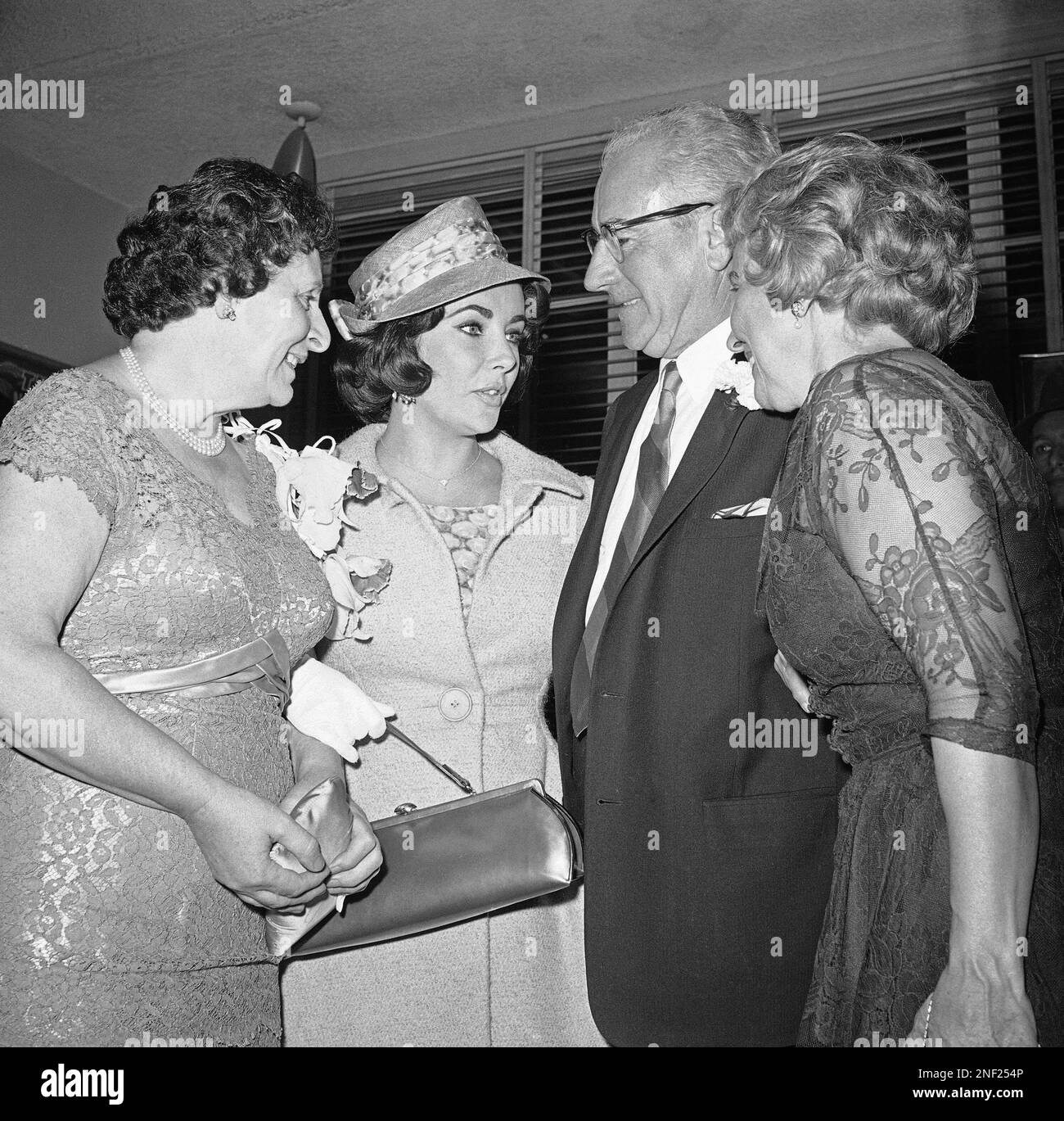 Elizabeth Taylor, center, and Eddie Fisher, not shown, say goodbye to her parents, Mr. Francis Taylor and Mrs. Sara Taylor, right, and to his mother, Mrs. Max Stupp just before beginning their honeymoon with a flight to Los Angeles, first leg of a trip that will take them to London, May 12, 1959, Los Angeles, Calif. (AP Photo) Stockfoto