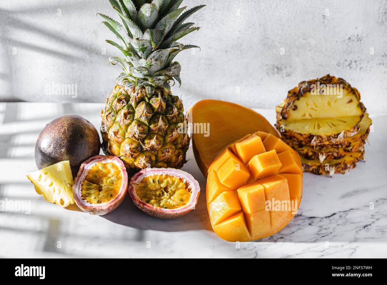 Verschiedene Früchte, Ananas, Mango und Passionsfrüchte. Thailändische Früchte auf einem hellen Tisch im Sonnenlicht Stockfoto