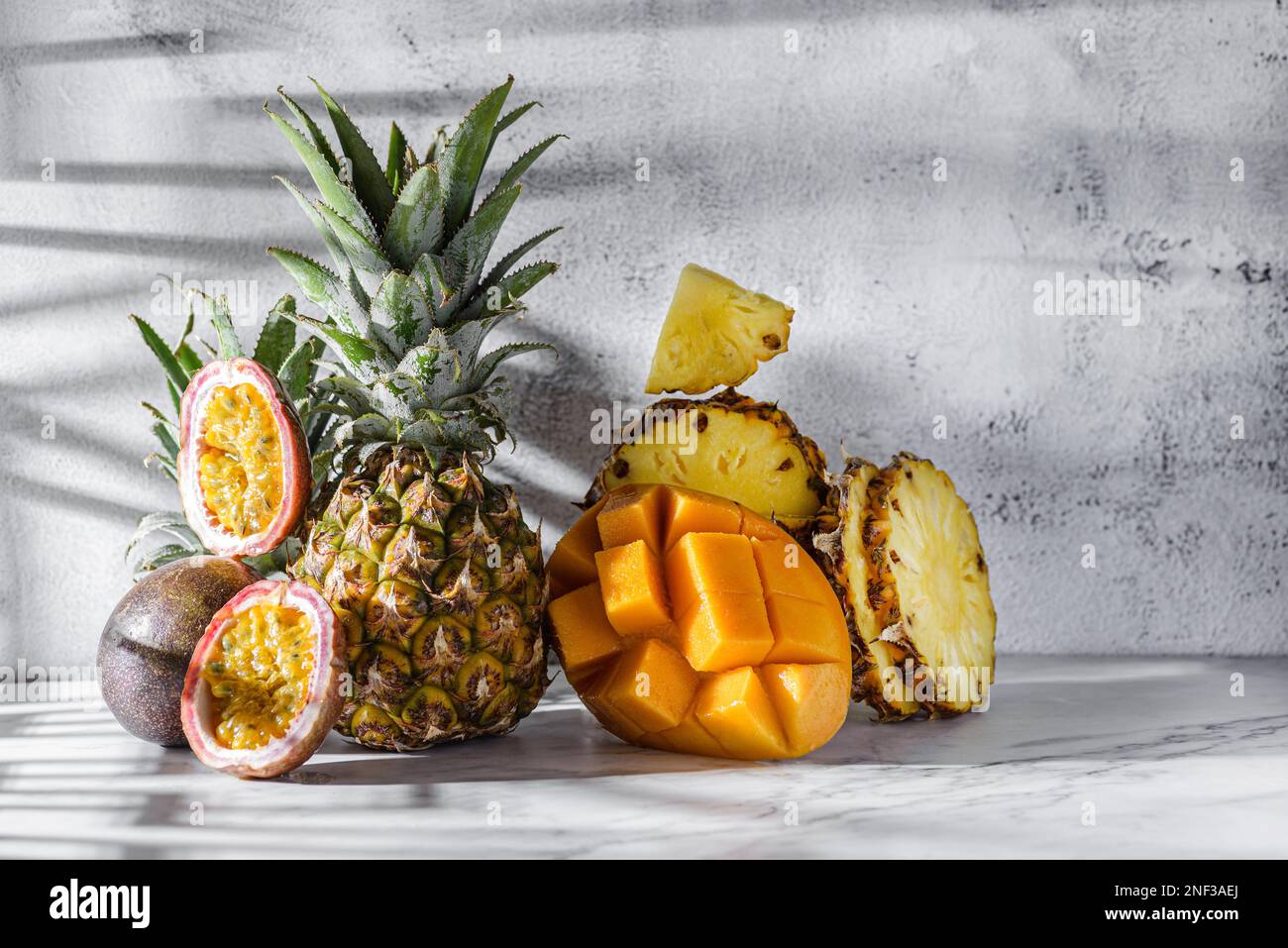 Verschiedene Früchte, Ananas, Mango und Passionsfrüchte. Thailändische Früchte auf einem hellen Tisch im Sonnenlicht Stockfoto