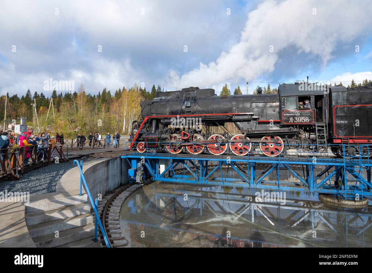 RUSKEALA, RUSSLAND - 09. OKTOBER 2022: Touristen beobachten, wie sich eine Dampflokomotive an einem Oktobernachmittag auf dem Drehteller dreht Stockfoto