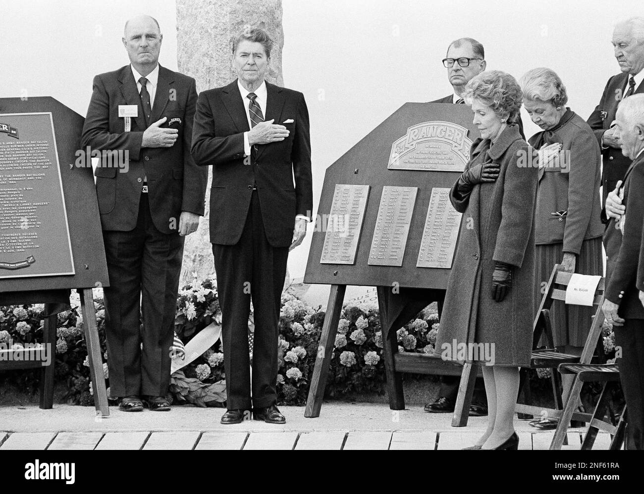 Pres. Ronald Reagan, second from left, and Mrs. Nancy Reagan, right, pause as anthems are played after the unveiling of a memorial plate for the 2nd Ranger Battalion that conquered Pointe du Hoc 40 years ago, during memorial ceremony, Wednesday, June 6, 1984, Pointe du Hoc, France. At the extreme right is Mrs. Margarethe Rudders, from Bryan, Texas, widow late Col. Earl Rudder, who was commander of the operation at Pointe du Hoc in 1944. He died in 1970. In the rear is Bill Brady, from Texas, chairman of the Rangers Veteran Association. (AP Photo) Stockfoto