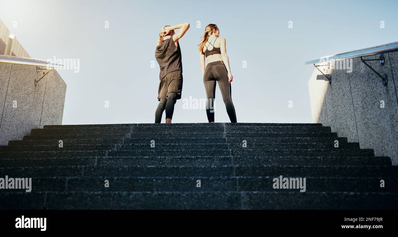 Es gibt keine Fahrstühle zum Fitness, nehmen Sie die Treppe. Rückansicht eines jungen Mannes und einer jungen Frau, die zusammen die Treppe in der Stadt hochlaufen. Stockfoto