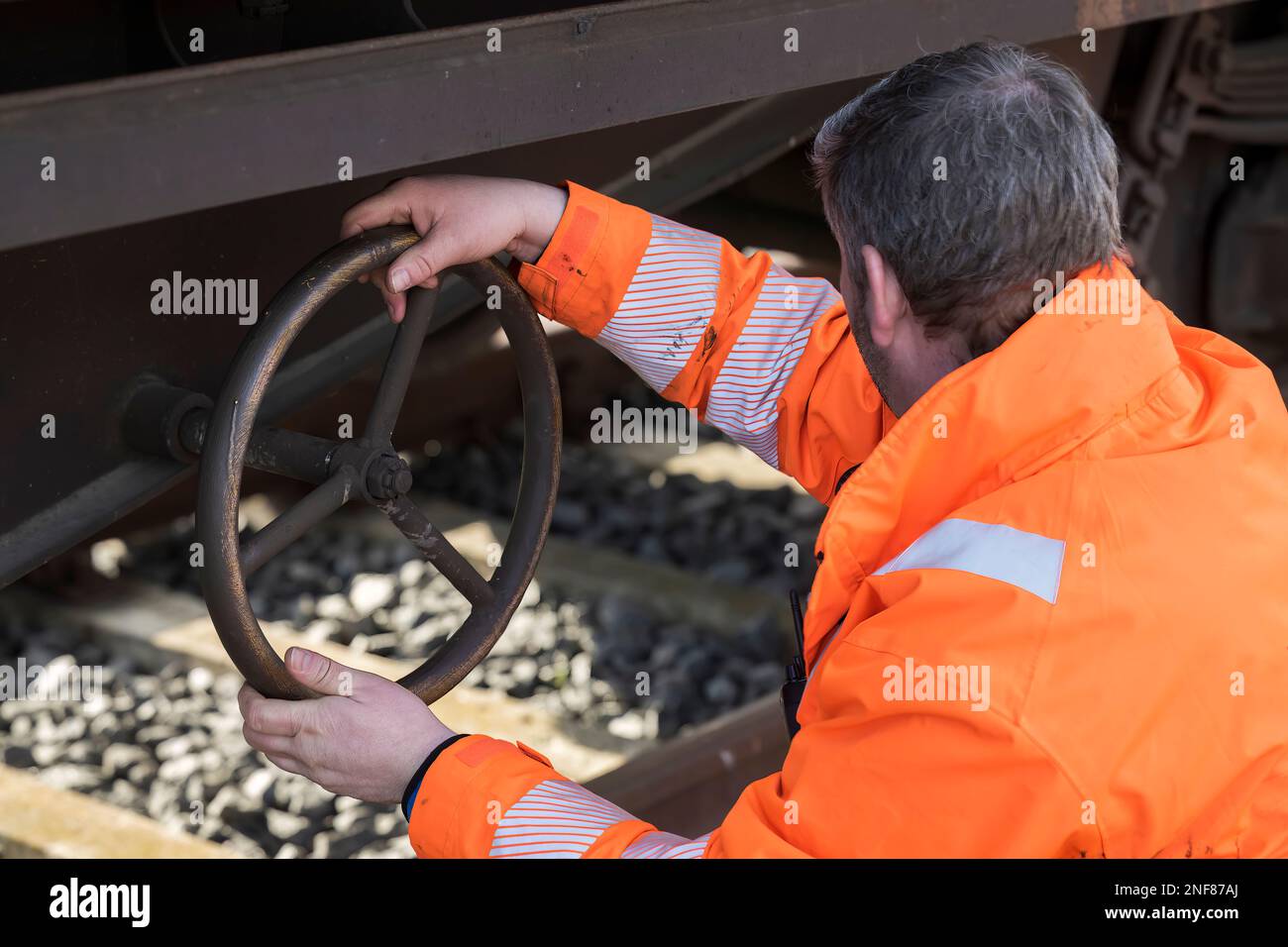 Ein Eisenbahnmitarbeiter betätigt eine Feststellbremse an einem Wagen Stockfoto