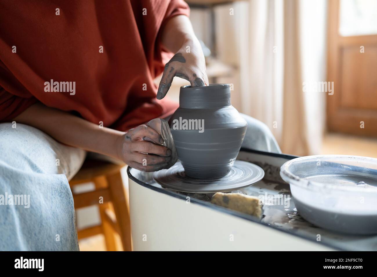 Handwerkerin genießt meditativen Prozess der Keramikherstellung, Formen von Lehm auf Töpferrad Stockfoto