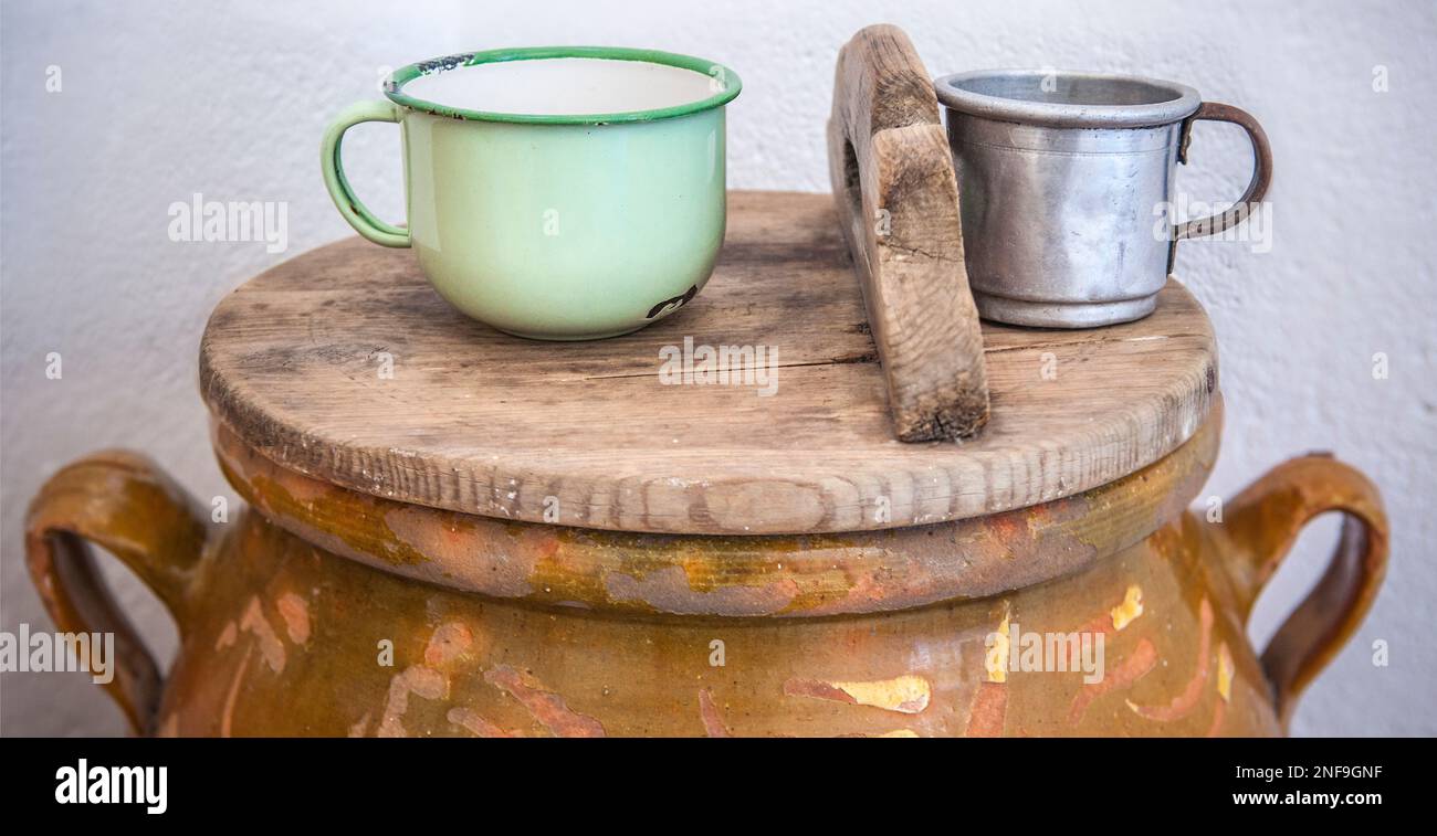 Großer Becher aus Steingut mit Deckel und Trinkwasserbecher. Altes Cottage Küchenkonzept Stockfoto