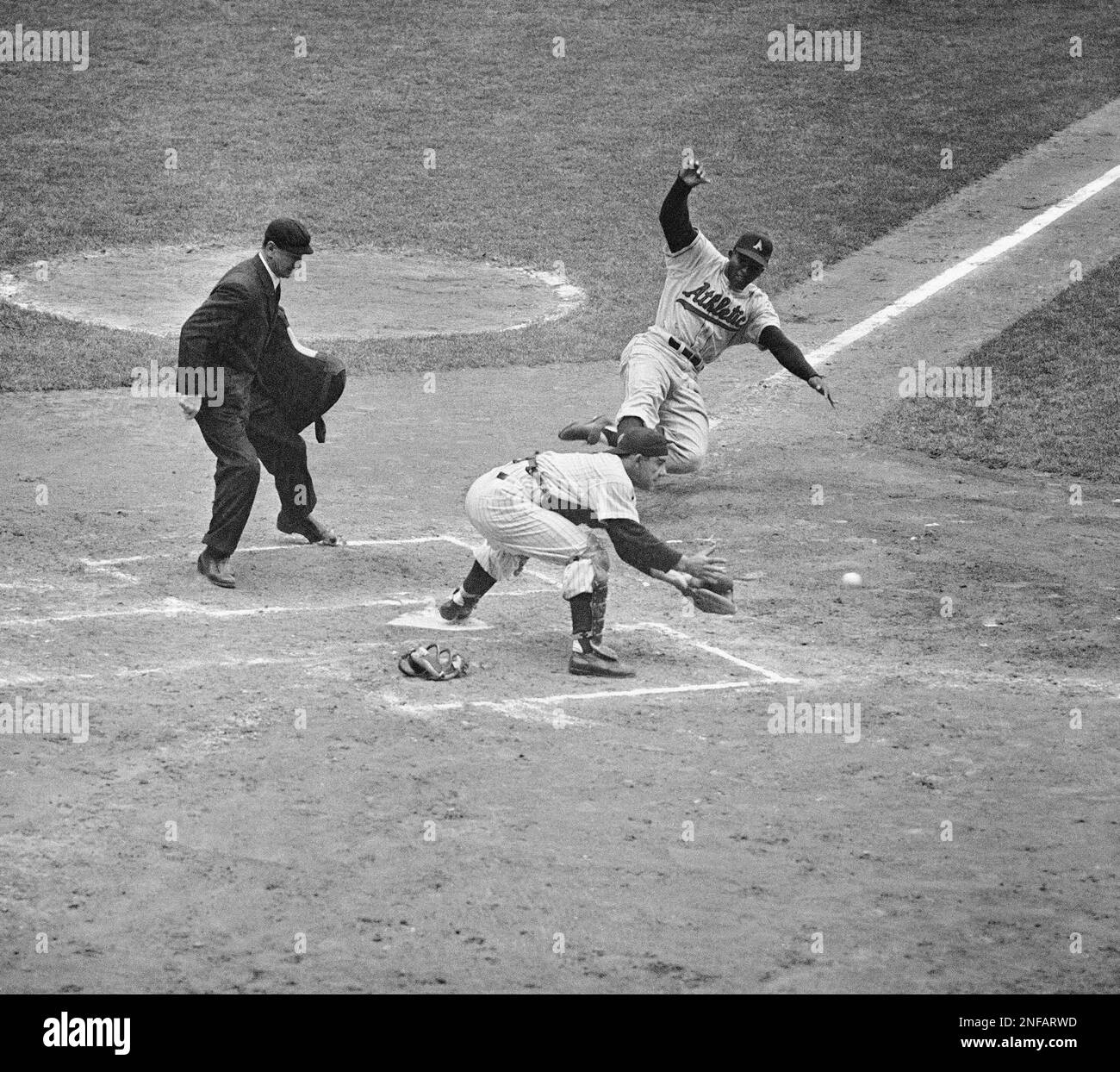 Vic Power of the Kansas City Athletics scores from third as Yankee catcher Yogi Berra takes throw from first baseman Bill Skowron in A's five-run second inning at Yankee Stadium in New York City, May 3, 1956. Power scored when Yankee pitcher Don Larsen tossed out A's pitcher Art Ceccarelli at first. Athletics won 8-7. (AP Photo/John Rooney) Stockfoto