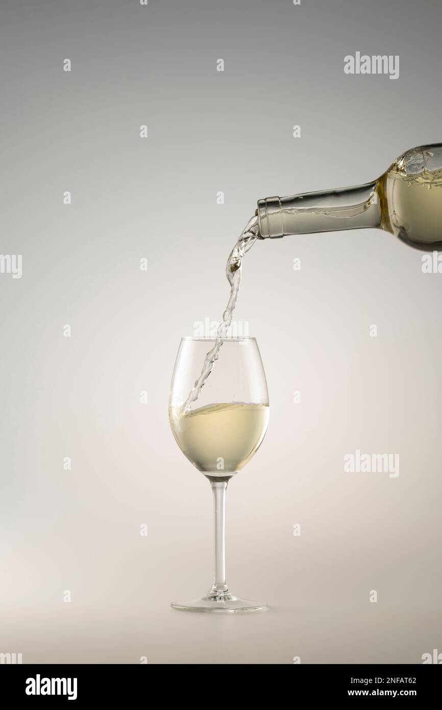 Weißwein wird in ein Weinglas gegossen Stockfoto