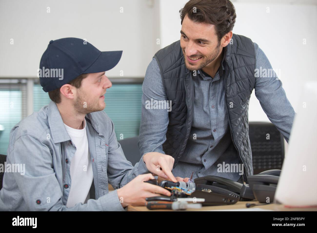Zwei Männer reparieren Mobiltelefone in einer modernen Werkstatt Stockfoto