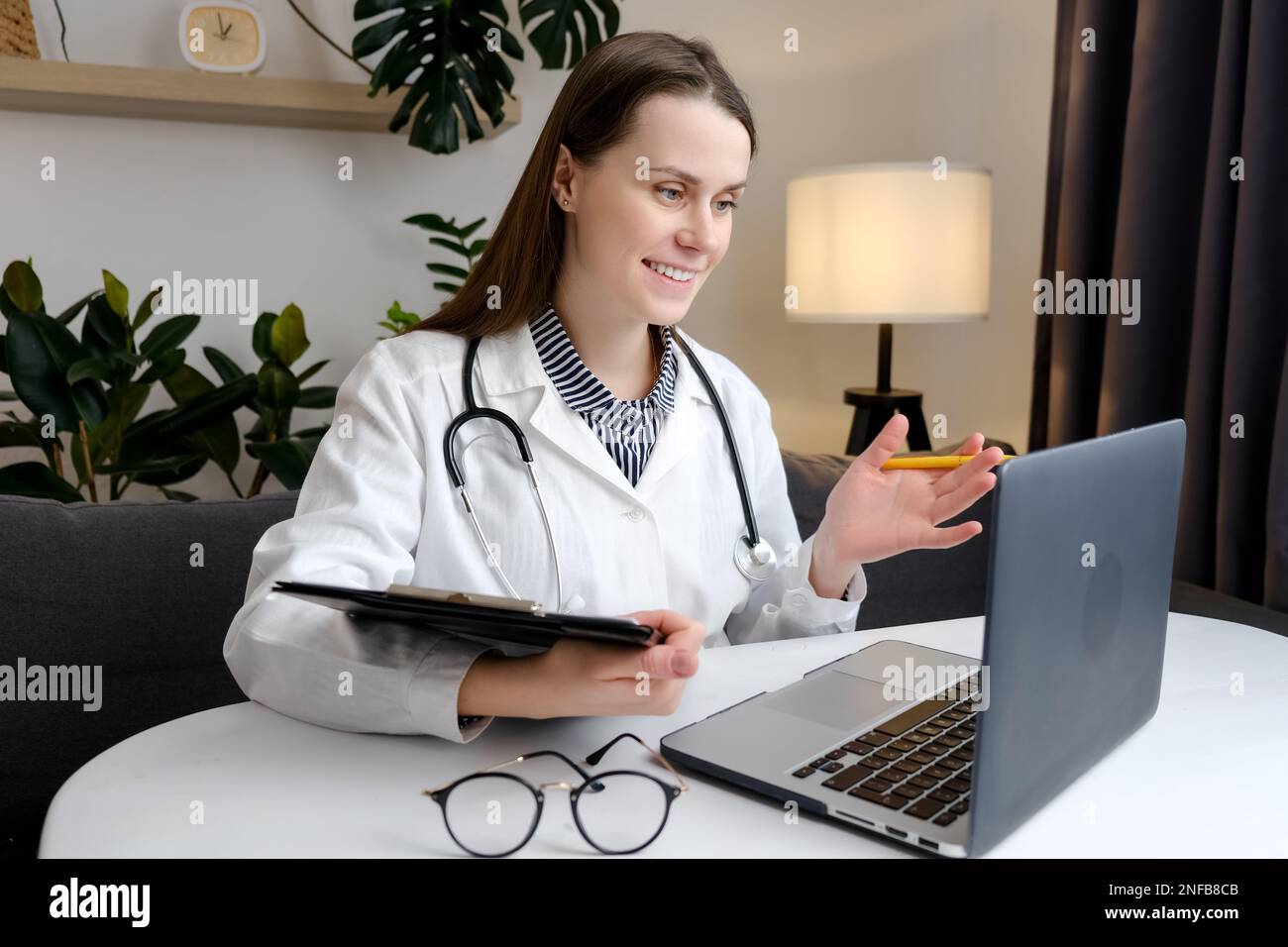 Telehealth-Konzept. Glücklicher, aufmerksamer Allgemeinarzt in Uniform und Stethoskop mit Laptop, Online-Hilfe, medizinische Unterstützung, Beratung, t Stockfoto