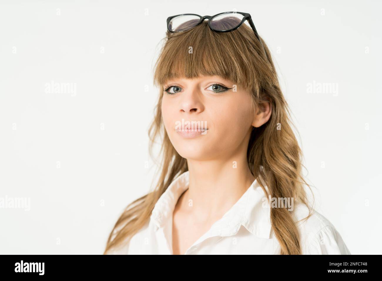 Eine Frau, die eine Sonnenbrille und lange, weiche Pony trägt, steht in einer legeren Pose Stockfoto
