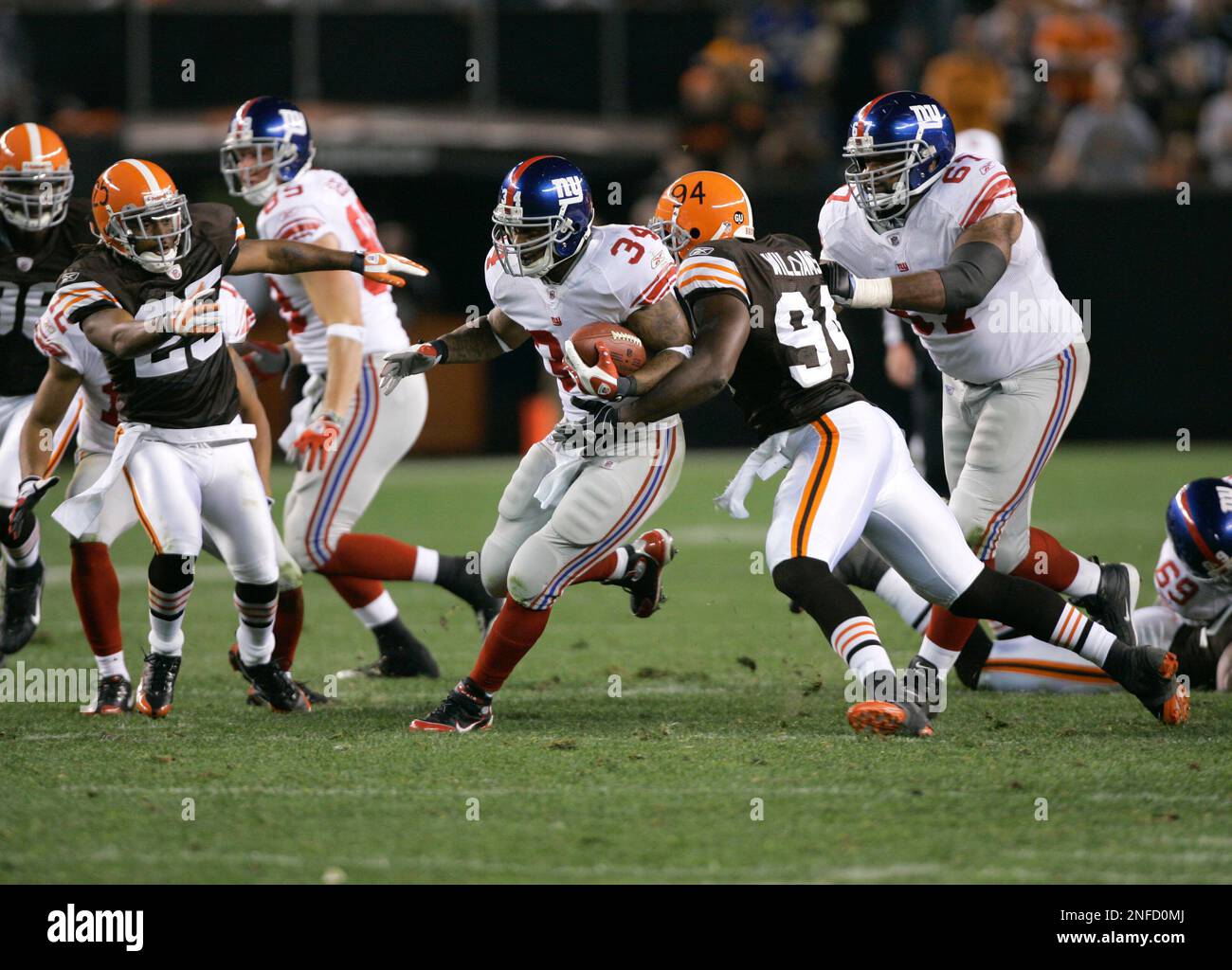 New York Giants running back Derrick Ward (34) runs with the ball as Cleveland Browns linebacker Leon Williams (94) and defensive back Terry Cousin (25) tackle during a NFL football game Monday, Oct. 13, 2008, in Cleveland. (AP Photo/Mark Duncan) Stockfoto