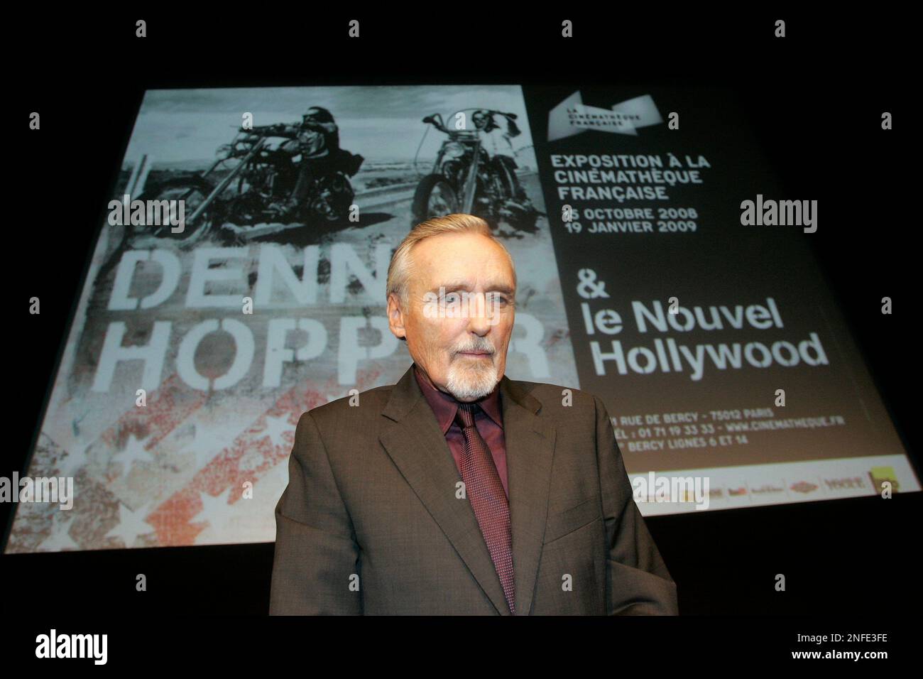 American actor and director Dennis Hopper poses in front of the poster of his exhibition following a press conference at the Cinematheque Francaise in Paris, Monday, Oct. 13, 2008. Dennis Hopper will be the subject of an exhibition, "Dennis Hopper and the New Hollywood," which will open Oct. 13 and run until Jan. 19, 2009, at the Cinematheque Francaise in Paris. (AP Photo/Michel Euler) Stockfoto
