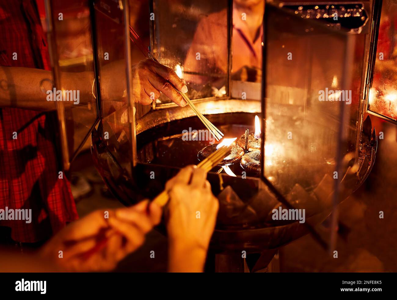 Menschen, die Weihrauch von Kerzenfeuer im Tempel anlässlich der chinesischen Neujahrsfeier in Bangkok, Thailand, verbrennen. Nahaufnahme der Hände Stockfoto