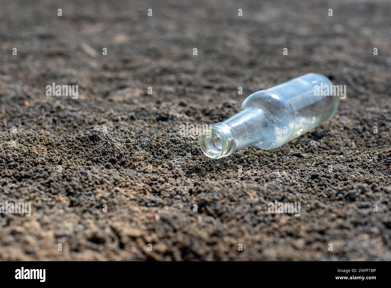 Glasflasche liegt auf dem Boden. Das Konzept des Wassermangels und der Dürre Stockfoto