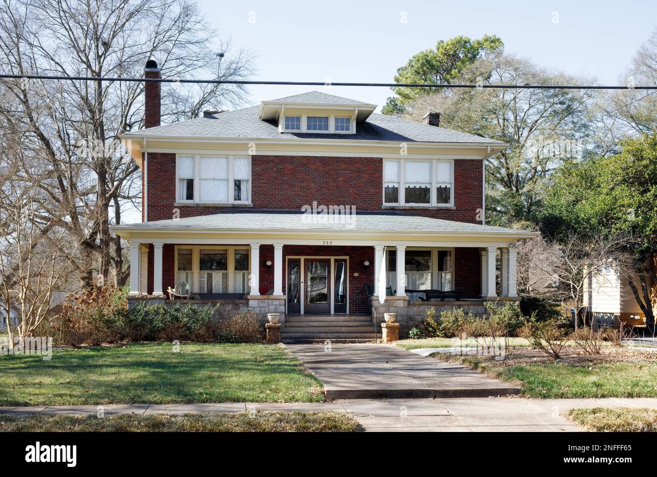 HICKORY, NC, USA-14. FEBRUAR 2023: Älteres 2 1/2-stöckiges Ziegelhaus im italienischen Stil in der Innenstadt, überdachte Veranda. Sonniger, blauer Himmel. Stockfoto