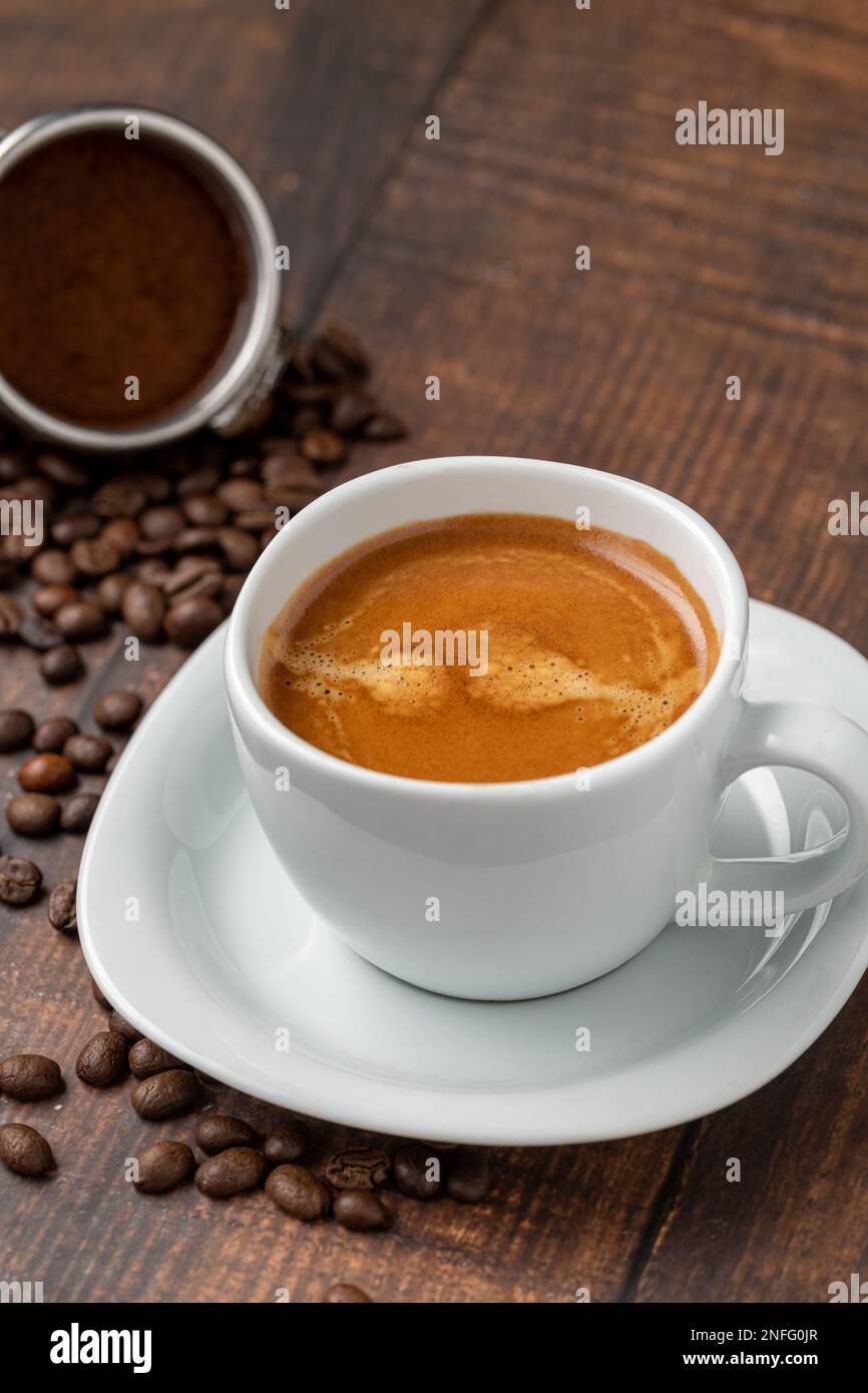 Frischer doppelter Espresso und Kaffeebohnen auf Holztisch Stockfoto