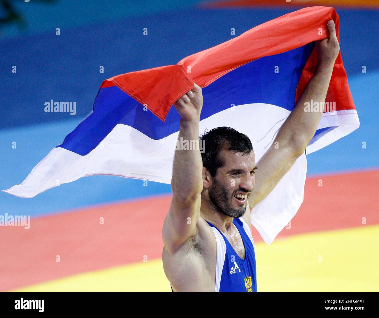 Russia's Buvaysa Saytiev celebrates with the Russian flag after winning his 74 kilogram freestyle wrestling gold medal match against Solan Tigiev, of Uzbekistan, at the Beijing 2008 Olympics in Beijing, Wednesday, Aug. 20, 2008. (AP Photo/Ed Wray) Stockfoto
