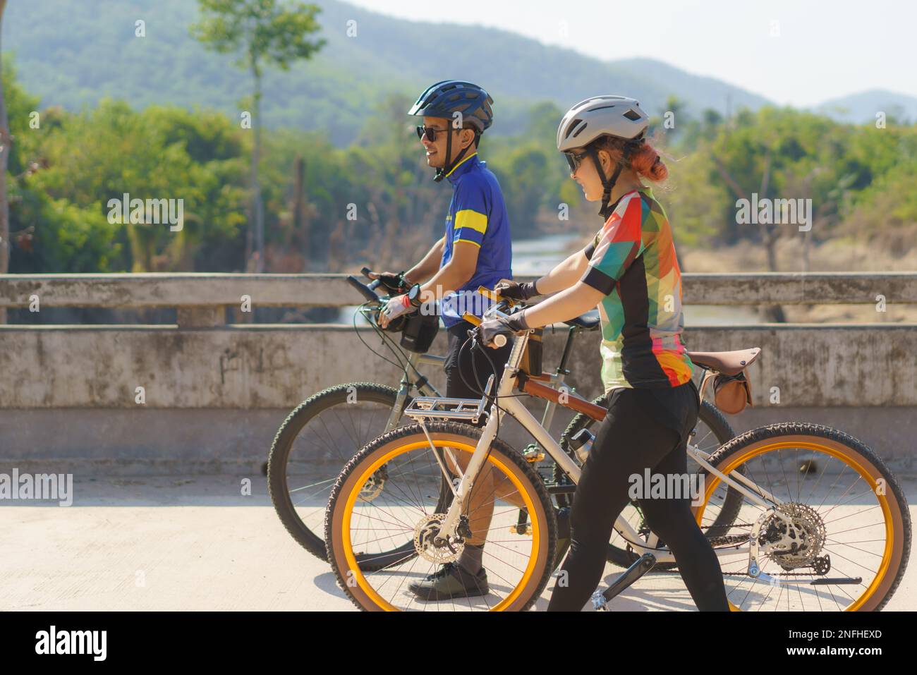 Asiatisches Fahrradpaar, das eine Pause vom Radfahren macht, macht eine Pause, geht spazieren und redet miteinander, um sich zu entspannen. Stockfoto