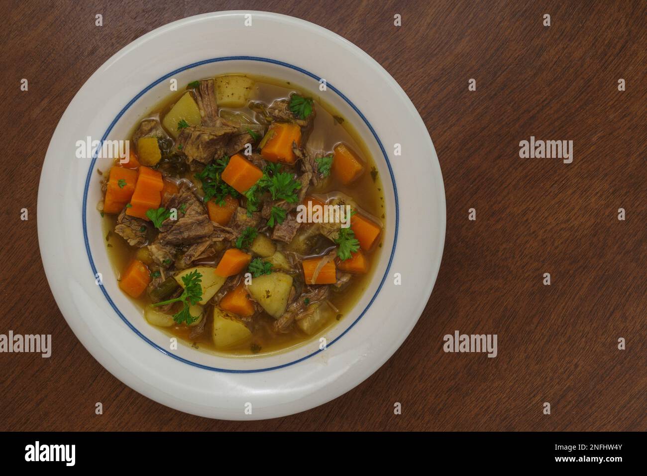 Traditionelle finnische Fleischsuppe mit Rindfleisch, Karotten und Kartoffeln. Weiße Platte auf Holzfläche. Stockfoto