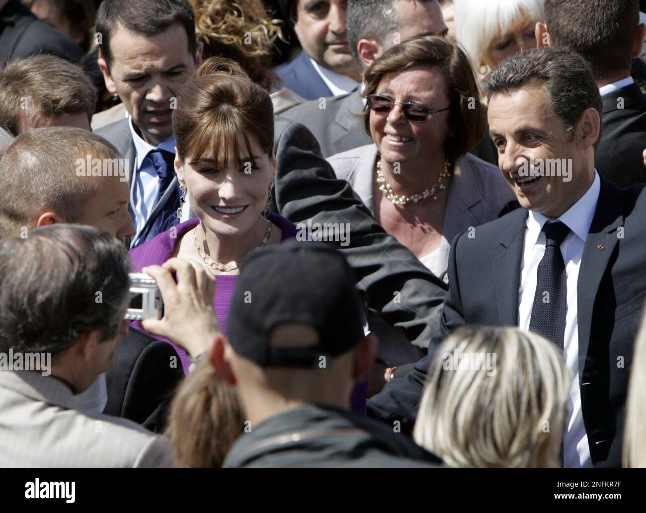 People take snapshots of French first lady Carla Bruni-Sarkozy with French President Nicolas Sarkozy, right, following the Bastille Day parade in Paris Monday July 14, 2008. Leaders from Europe, the Middle East and North Africa and the head of the United Nations gather in Paris for France's Bastille Day military parade, one day after their Mediterranean Summit in the city. (AP Photo/Remy de la Mauviniere) Stockfoto