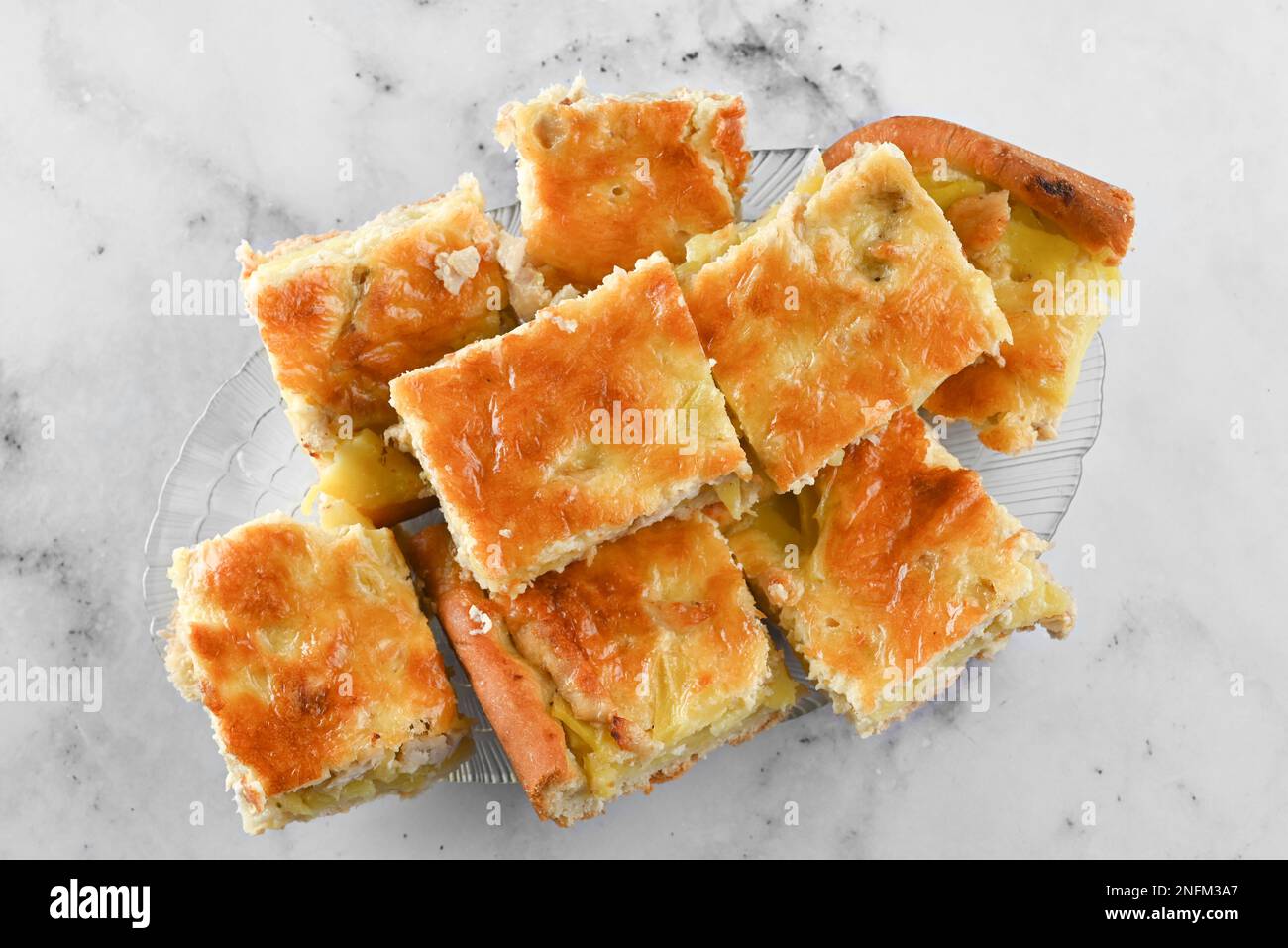 Gericht mit Hühnchen und Kartoffelkuchen auf hellem Hintergrund. Eine Portion hausgemachter Kuchen auf einem weißen Teller auf einem hellen Tisch Stockfoto