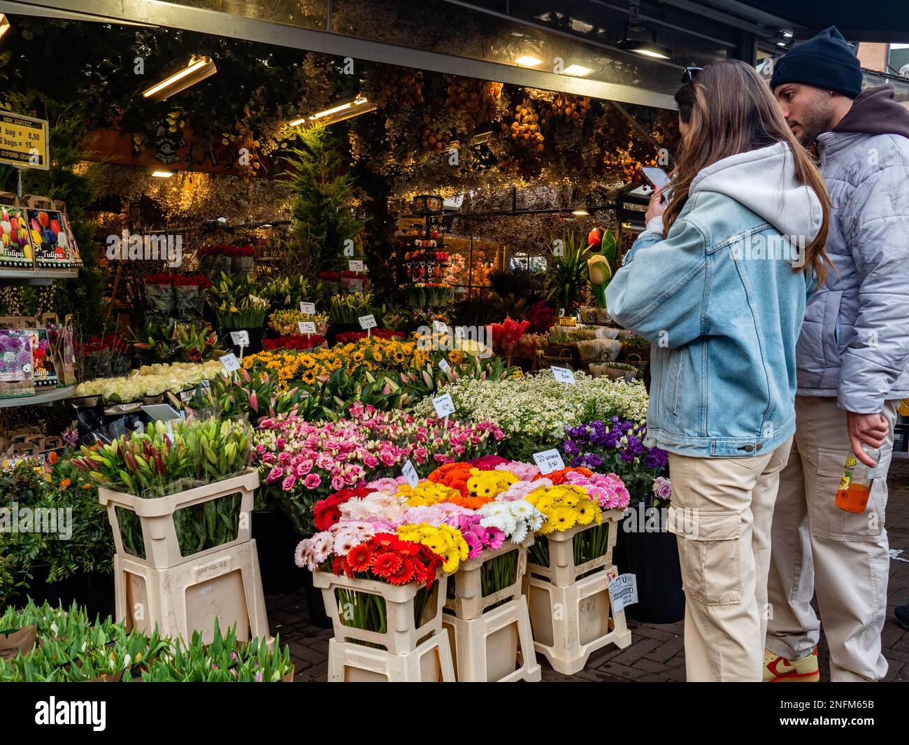 Eine Frau wird dabei gesehen, wie sie Fotos in einem der Blumenstände macht, die zum Blumenmarkt gehören. Amsterdam ist eine der schönsten, kreativsten und fahrradfreundlichsten Städte Europas. Es hat eine tolle Mischung aus kosmopolitischem Flair und relativ klein, was bedeutet, dass es einen Dorfcharme hat. Obwohl es immer noch kalt, aber sonnig ist, besuchen Touristen bereits die niederländische Hauptstadt an Wochentagen. Die am häufigsten besuchten Orte sind in der Regel der Dam-Platz, das Stadtzentrum und die Museen und Kanäle. (Foto: Ana Fernandez/SOPA Images/Sipa USA) Stockfoto