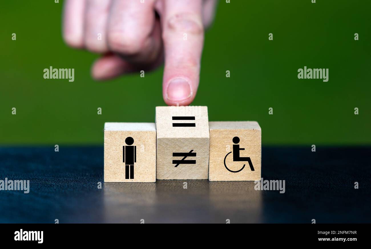 Symbol für die Gleichberechtigung von Menschen mit Behinderungen. Die Hand dreht den Holzwürfel und ändert das Gleichheitszeichen in ein Gleichheitszeichen. Stockfoto