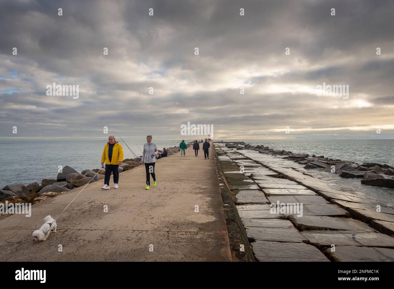 Menschen, die am Wellenbrecher in Portimao, Algarve, Portugal spazieren Stockfoto