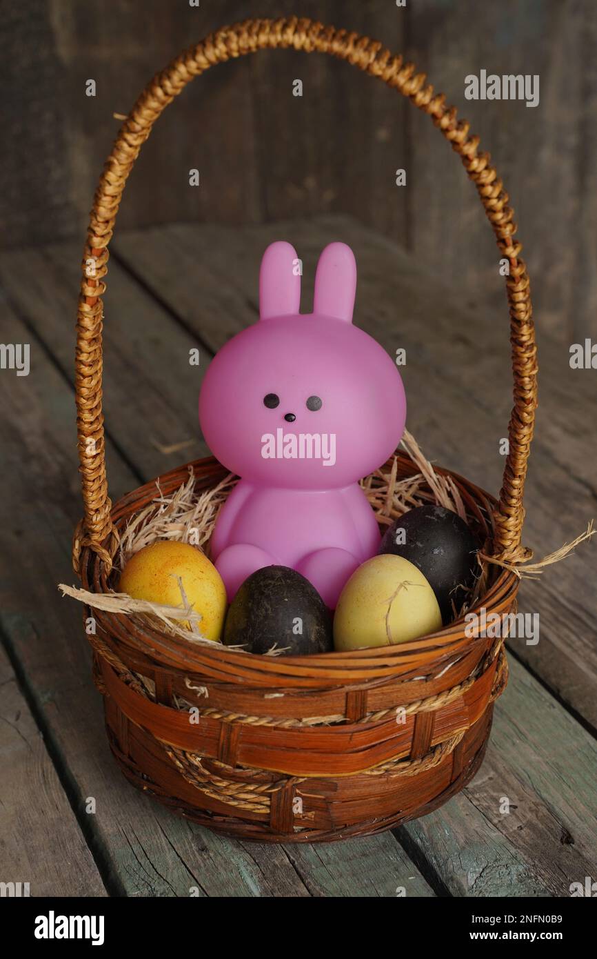 Hase oder Hase und bunte Esthers Eier im Korb. Süßes kleines rosa Kaninchen und Esthers Eier auf Holzhintergrund. Rabit steht Stockfoto