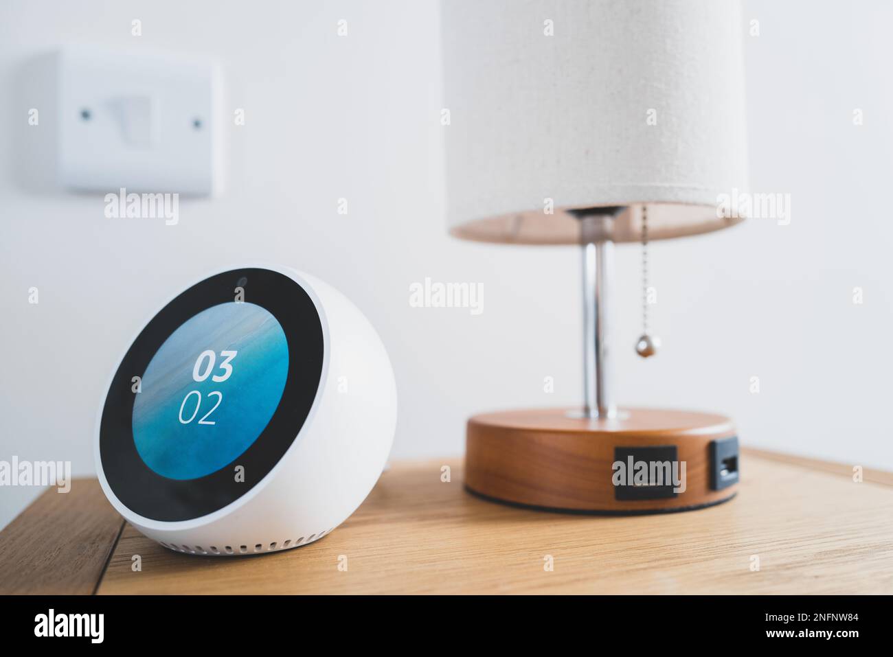 Smart-Gerät am Bettmonitor zeigt die Ortszeit an. Befindet sich neben einer Lampe mit USB-Ladeanschlüssen Stockfoto
