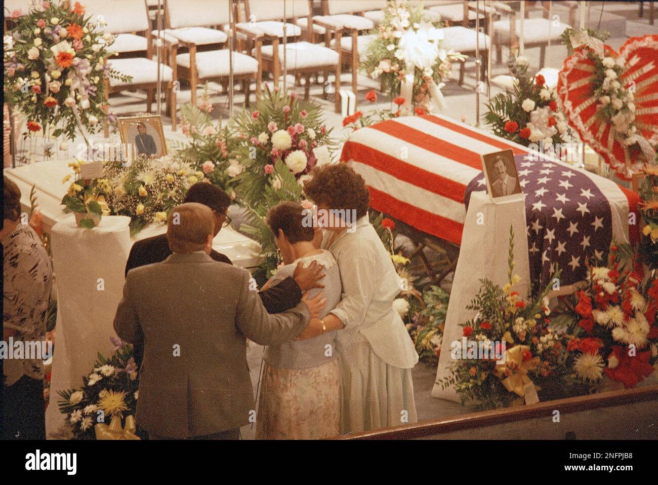 Family members console each other as they view coffins inside the First