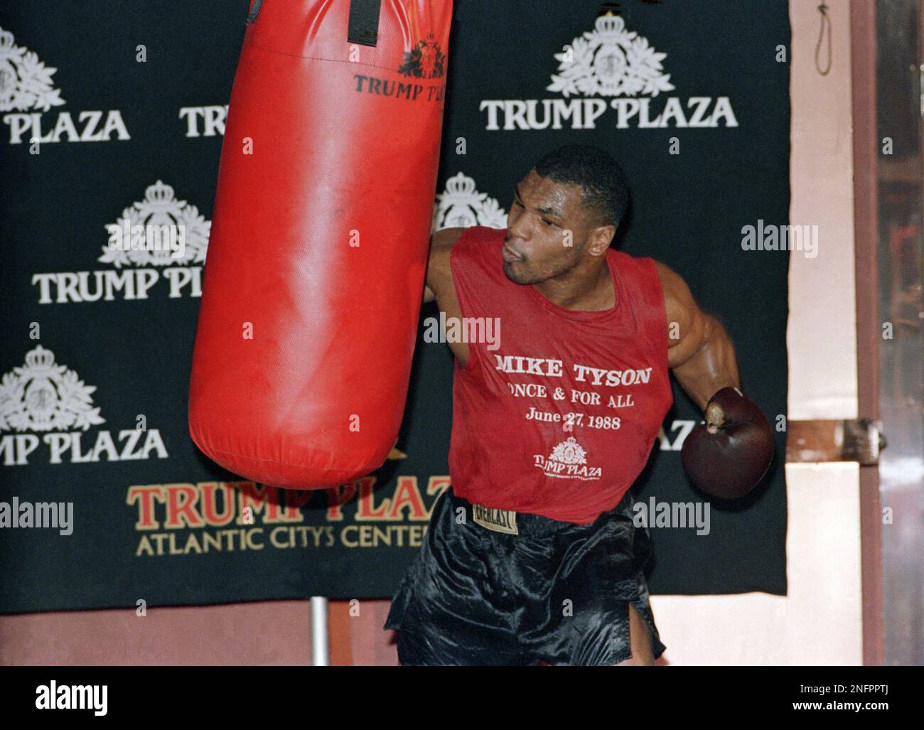 Heavyweight boxing champion Mike Tyson punches the heavy bag during a workout under the eyes of his trainer Kevin Rooney on Thursday, June 24, 1988 in Atlantic City. Tyson faces challenger Michael Spinks in a title bout on Monday June 27 in Atlantic City. (AP Photo/Michael Baytoff) Stockfoto