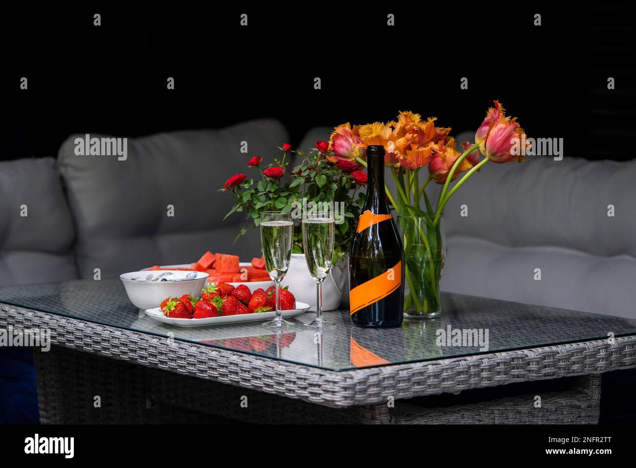 Romantisches Abendessen auf dem Tisch mit Champagner, Erdbeeren und Blumen. Stillleben mit Rosen Stockfoto