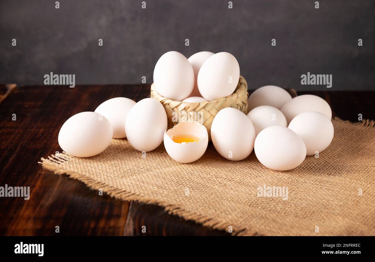 Viele weiße Hühnereier auf einem rustikalen Holztisch. Sehr beliebtes nahrhaftes und wirtschaftliches Lebensmittelprodukt. Stockfoto