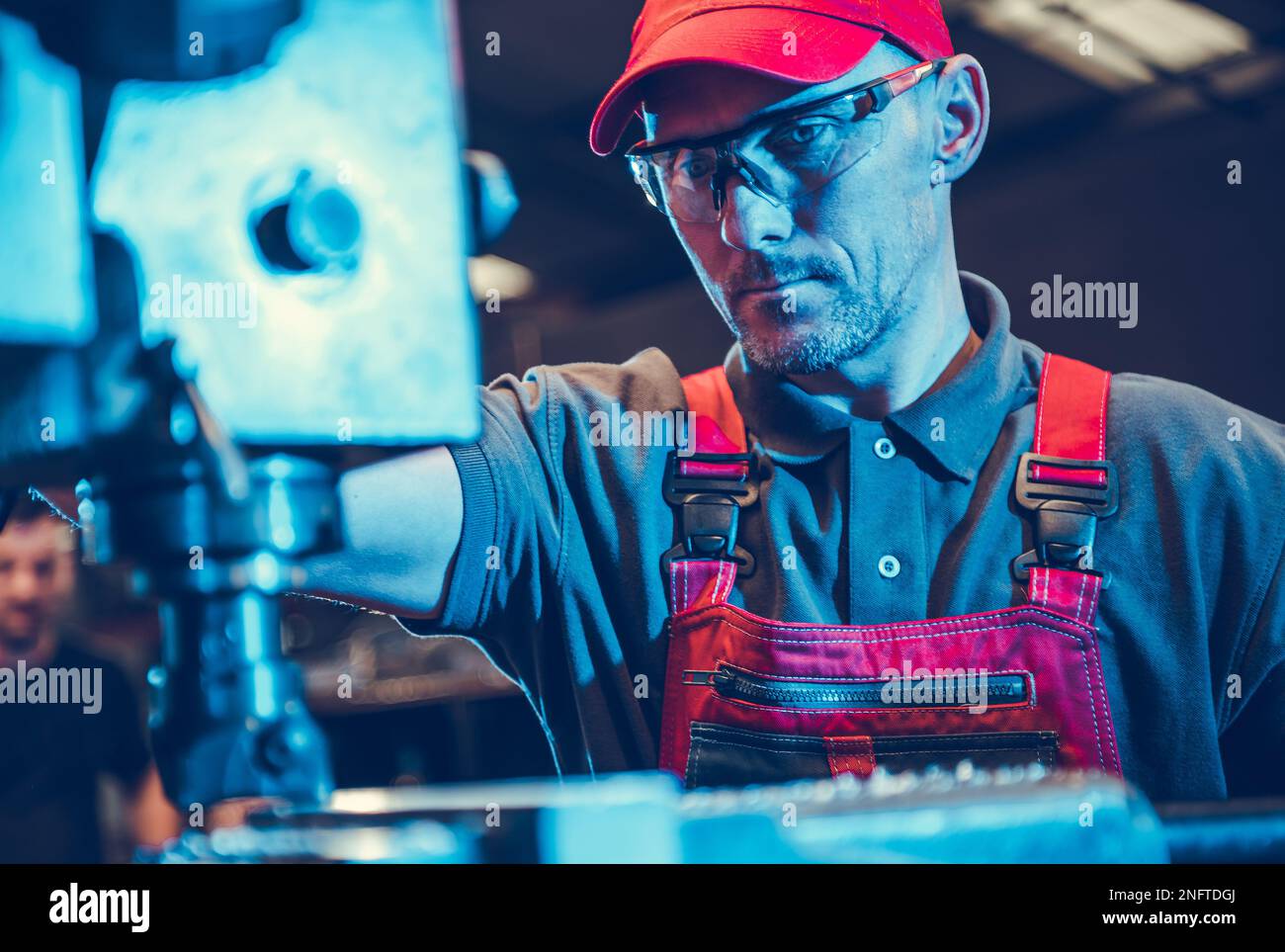 Professioneller, kaukasischer CNC-Fräsmaschinenbediener, der sich in seiner Werkstatt auf den Schneideprozess konzentrierte. Thema „Industrietechnologie“. Stockfoto