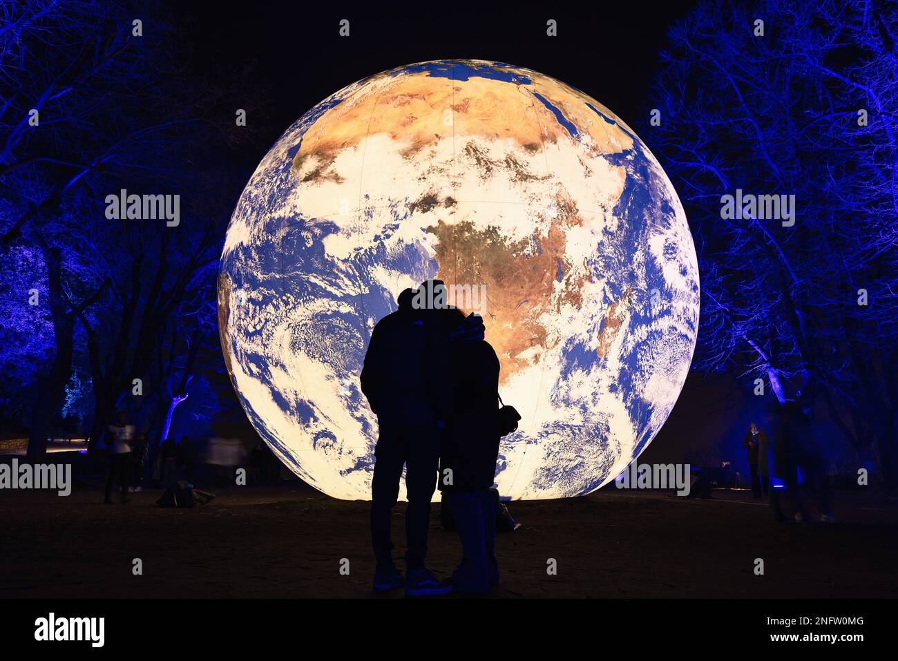 Brescia - Italia. 15. Februar 2023: Light is Life (Festa delle Luci A2A), Paar, das sich im Hintergrund von „Floating Earth“ von Luk aneinander klammert Stockfoto