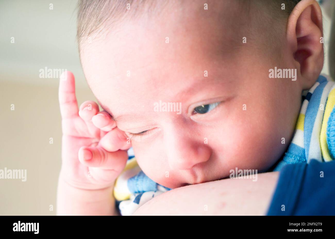 Ein kleiner Junge mit blauen Augen, der in den Armen der Mutter gehalten wird Stockfoto