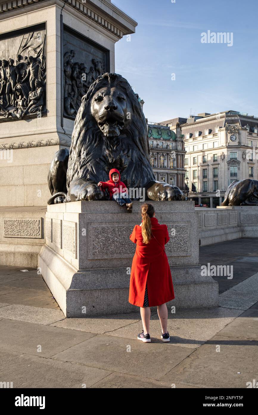 Frau, die ein Foto von einem Kind auf Nelsons Säule am Trafalgar Square in London macht Stockfoto