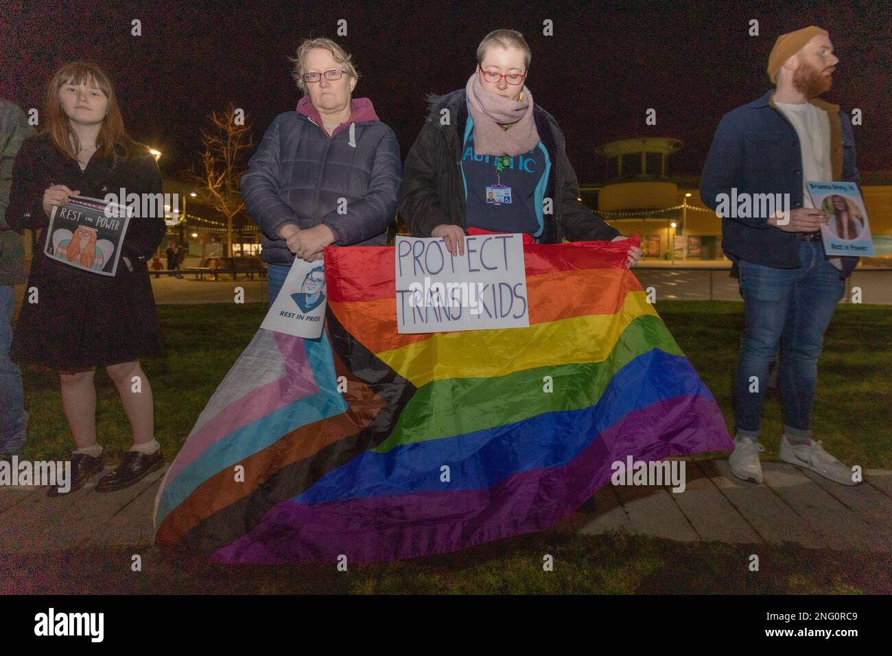 Basildon, Großbritannien. Februar 2023. Nächtliche Demonstration in Basildon für Transgender-Jugendschutz. Die Teilnehmer halten Stolz-Flaggen und Plakate mit „Protect Trans Kids“, die auf einem Holzsteg in der Nähe von Bürgerhäusern stehen. Die Bewohner kommen zu einer Mahnwache für Brianna Ghey zusammen, die am Samstag, den 11. Februar, in Warrington Park, Cheshire, ermordet wurde. Penelope Barritt/Alamy Live News Stockfoto
