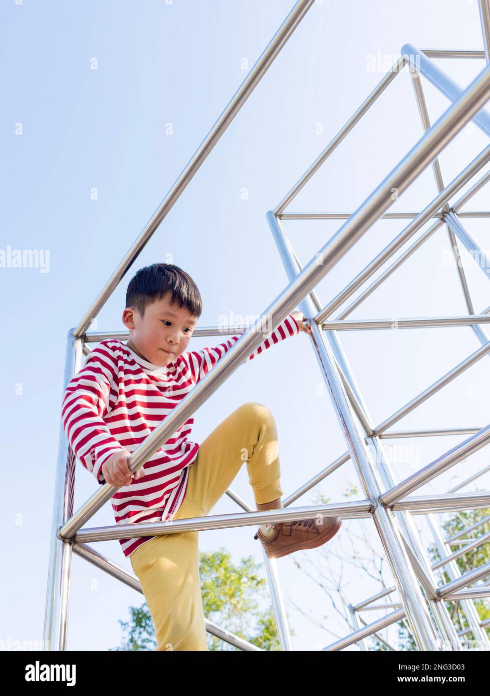 Ein kleiner Junge klettert auf einen öffentlichen Spielplatz. Es war im Daan Public Park in Taipei, Taiwan. Stockfoto