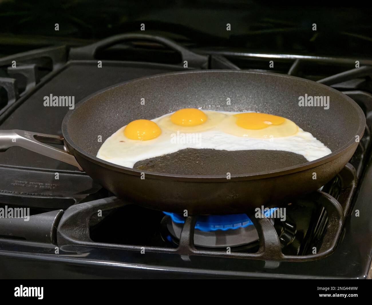 Eier, die in Pfannkuchen oder Bratpfannen braten, um sie in einem Haus in den USA auf einem Gasherd oder Herd zu kochen. Stockfoto