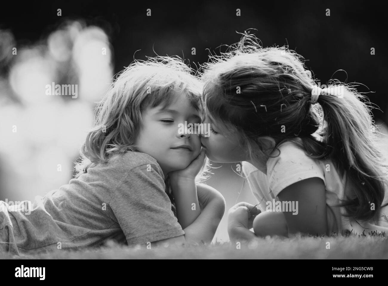 Nette Liebe. Kleines Mädchen küssen junge im Freien im Park. Beziehungen zu Kindern. Stockfoto