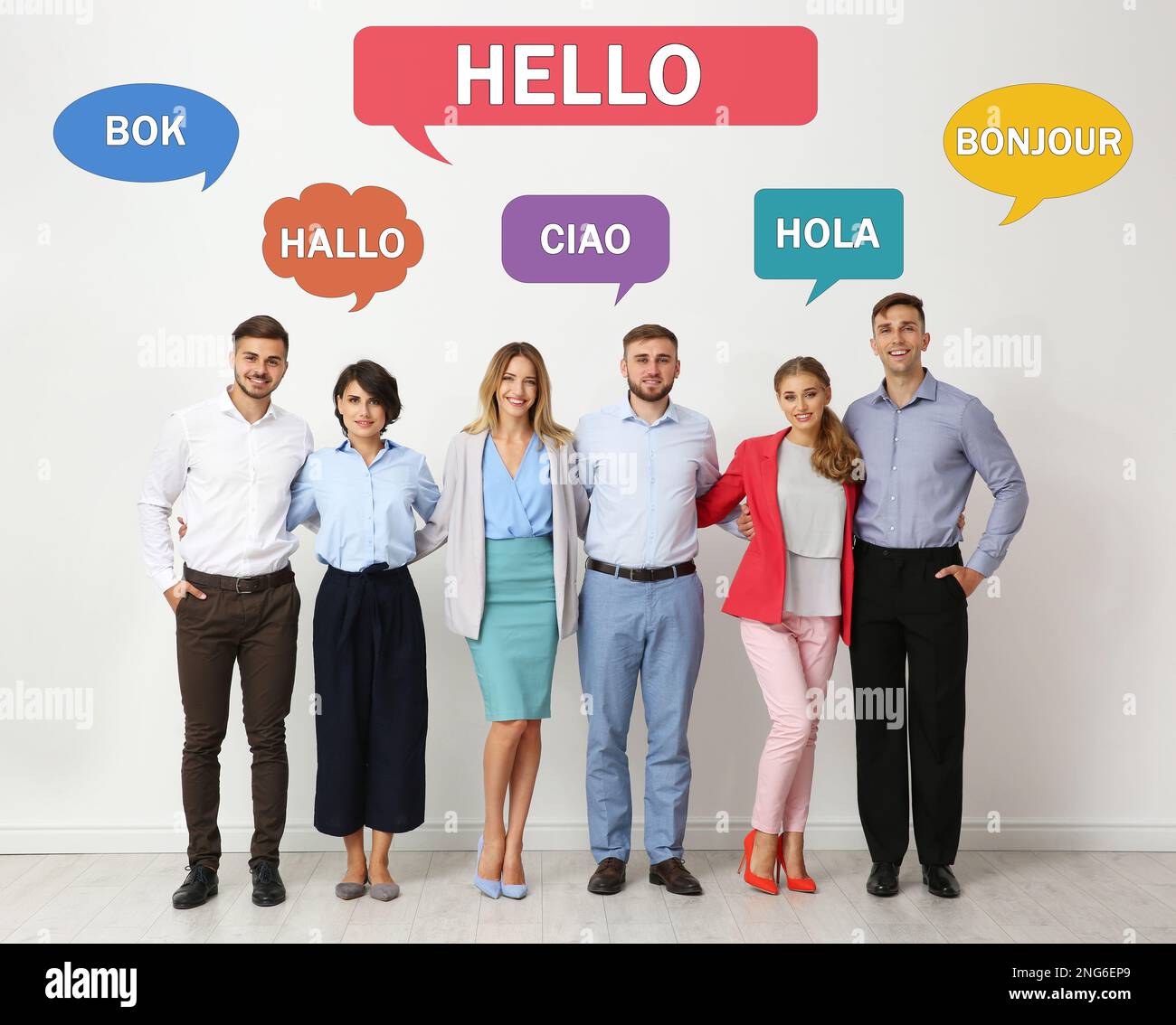 Fröhliche Leute, die neben einer hellen Wand posieren und Sprechblasen mit dem Wort „Hallo“ in verschiedenen Sprachen illustrieren Stockfoto