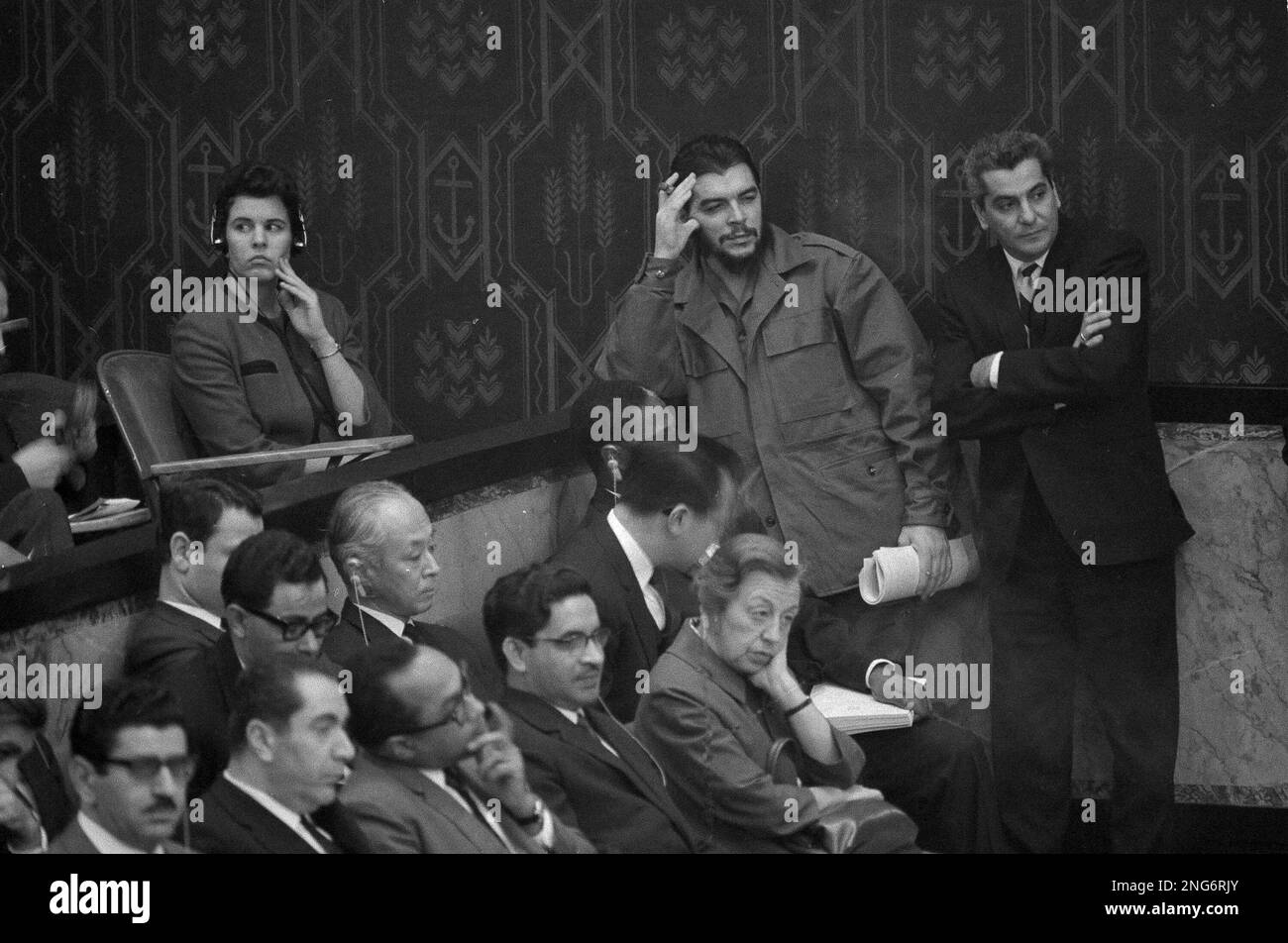 Cuba's Economic Minister Ernesto "Che" Guevara, smoking a cigar and in fatigues, leans against a wall in the spectator's gallery in the United Nations Security Council chamber, Dec. 14, 1964, in New York. He listens to a speech by U.S. Ambassador to the U.N. Adlai Stevenson. Cuba does not have a seat in the Security Council. (AP Photo/Harry Harris) Stockfoto