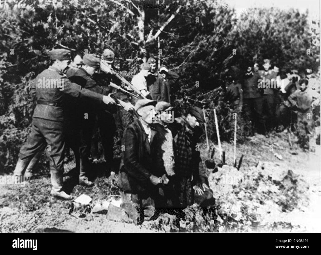 Die Anfangsphase des Holocaust war nicht mit Gaskammern, sondern mit mobilen Hinrichtungstruppen namens Enisatzgruppen. Ihre Aufgabe war es, hinter der Front zu streiten und alle Juden zu erschießen, die sie kriegen konnten. Sie töteten schätzungsweise zwei Millionen Menschen. Dieses Foto zeigt die Männer, die auf ihre Opfer schießen, knien an einem Graben, in den ihre Körper fallen werden. Stockfoto