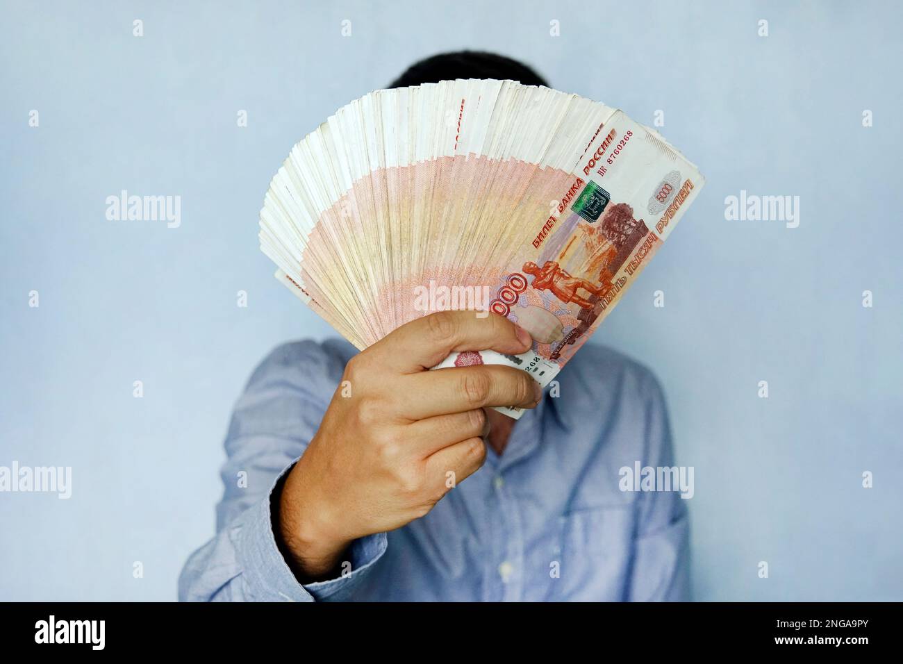 Stapel von Banknoten 5 000 russische Rubel in der Hand des Menschen auf blauem Hintergrund. Bündel Banknoten von 5000 Rubel der Russischen Föderation. Stockfoto